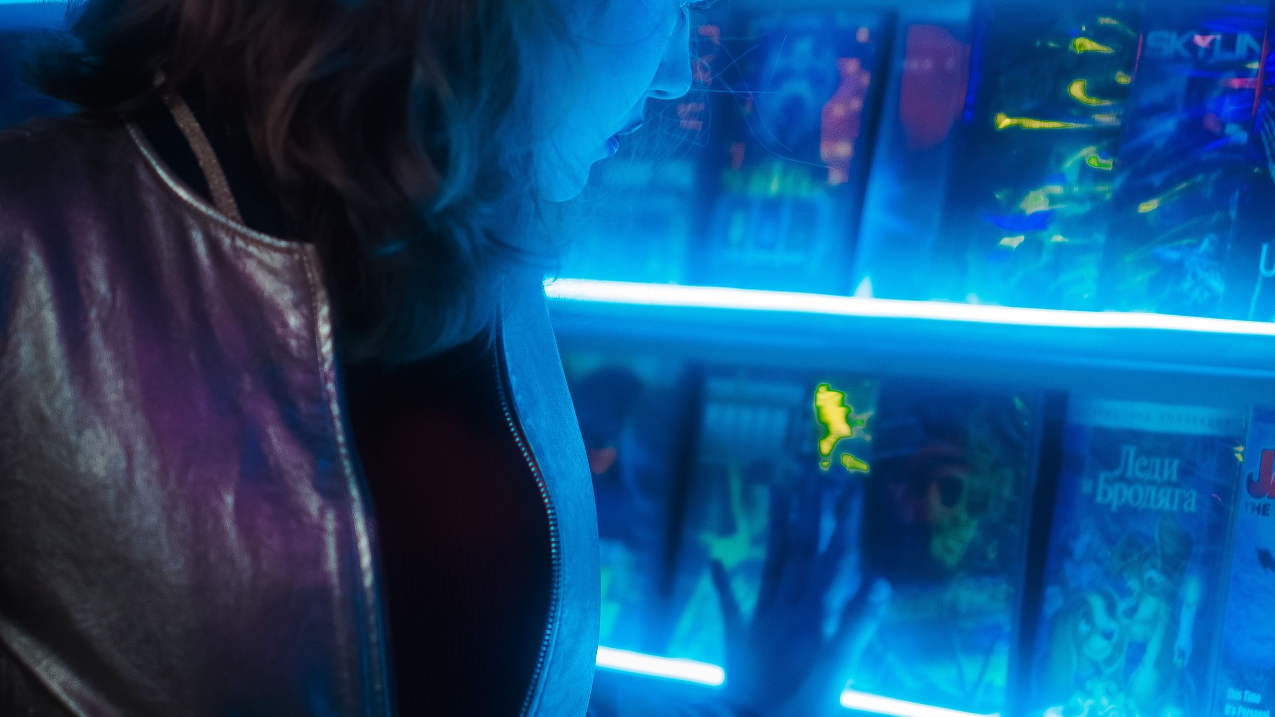 A woman in a neon jacket browses a bookshelf filled with sci-fi thrillers, showcasing her passion for the genre.